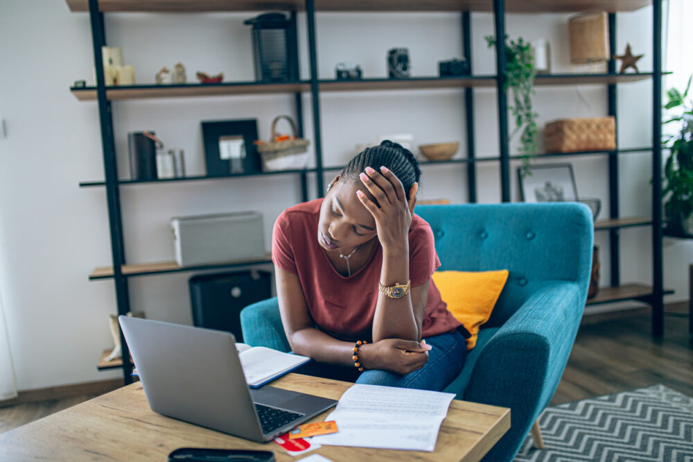 Young African woman taking a break from doing home finances and feeling stressful